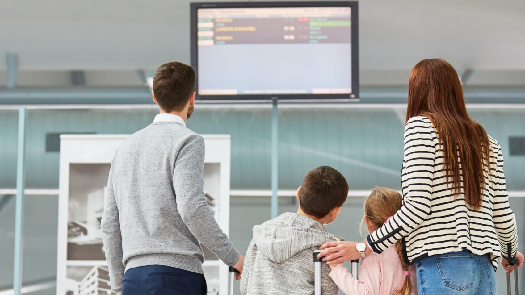 Family checking departure screens amid airline cancellations