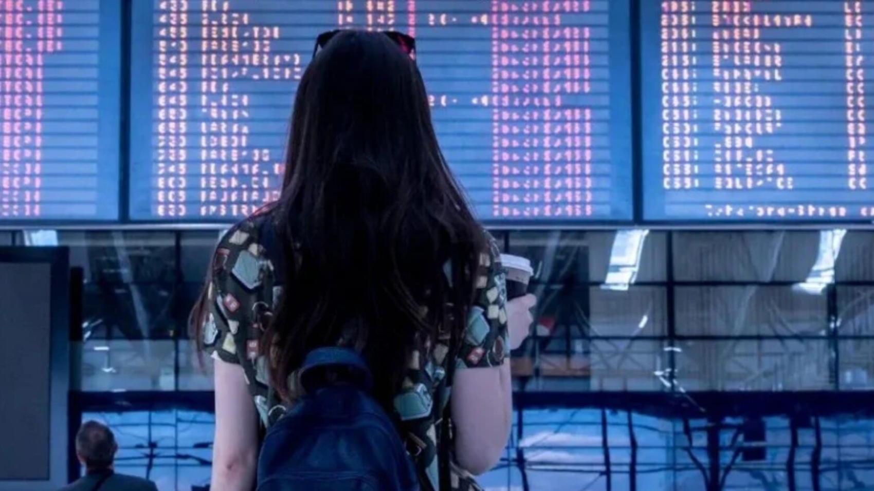 Passenger checking airport departure board during flight delays