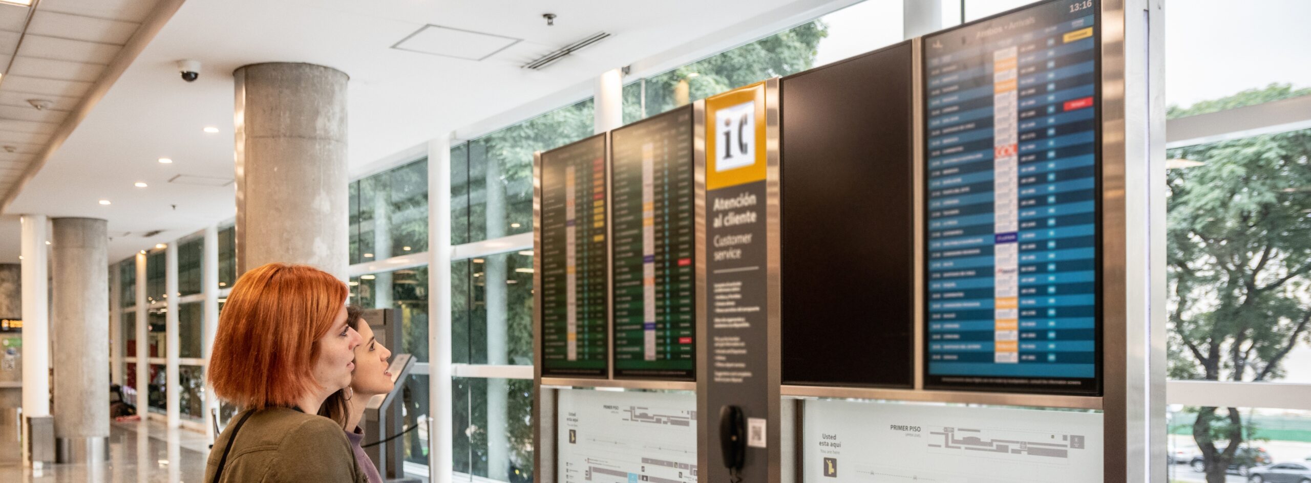 Close view of passengers tracking schedules on digital boards—airline disruption management software.