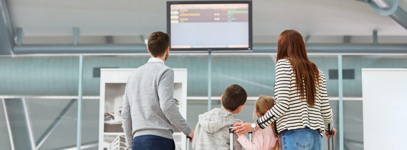 Family checking departure screens amid airline cancellations